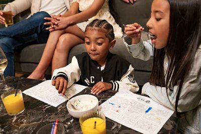 Two children colouring and eating ice cream