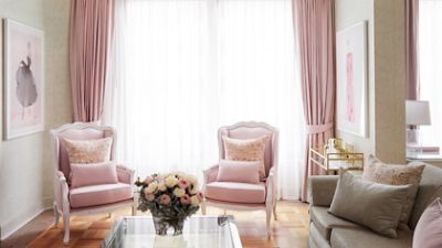 Indulge in the Kerrie Hess Residence Suite, the spacious living space is elegantly furnished in pink and white.