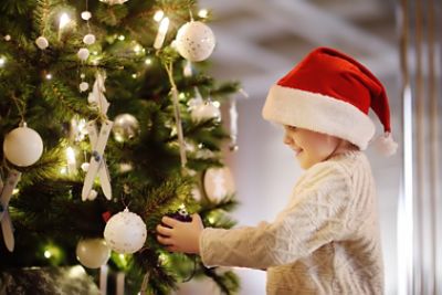 Young boy hanging ornaments on a Christmas Tree