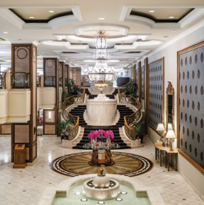 The Langham, Melbourne luxury 5-Star hotel's lobby with a timelessly elegant grand marble staircase and crystal chandelier.